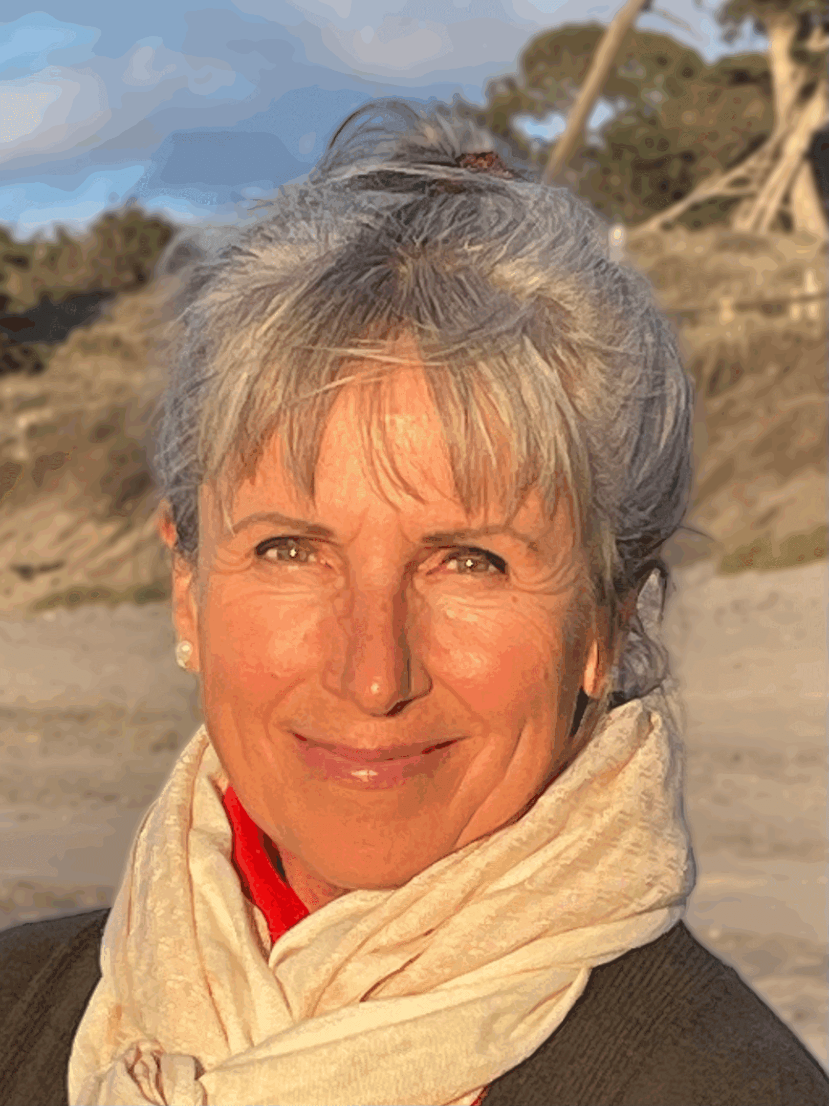Smiling woman with gray hair outdoors at sunset.